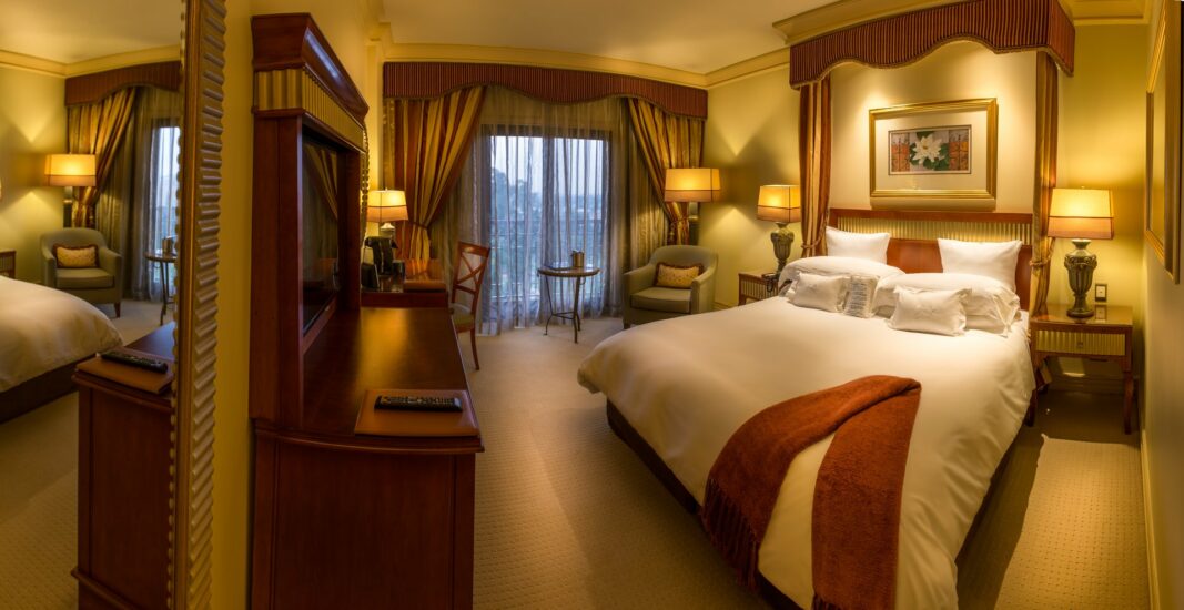 Club Floor Deluxe room with draped king bed and balcony doors at the D'oreale Grande, Emperors Palace