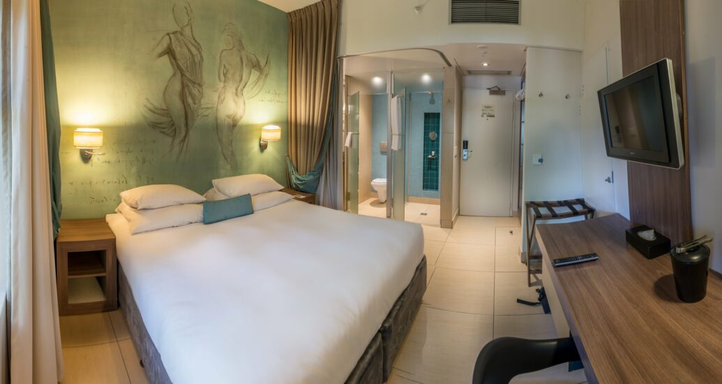Classic King Room ensuite with glass shower and wall-mounted TV at Metcourt, Emperors Palace