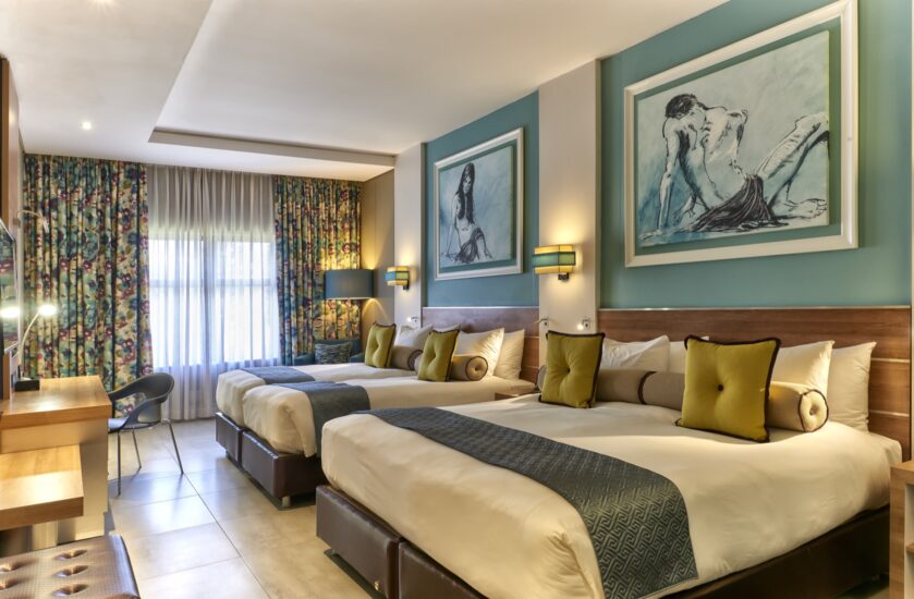 Metcourt family room with three beds, teal walls and sketch artwork at Emperors Palace