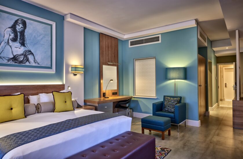 Metcourt guest room with double bed, work desk and blue armchair at Emperors Palace