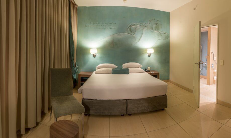 A twin-bedded accessible room with a mermaid mural and open ensuite bathroom at Metcourt, Emperors Palace